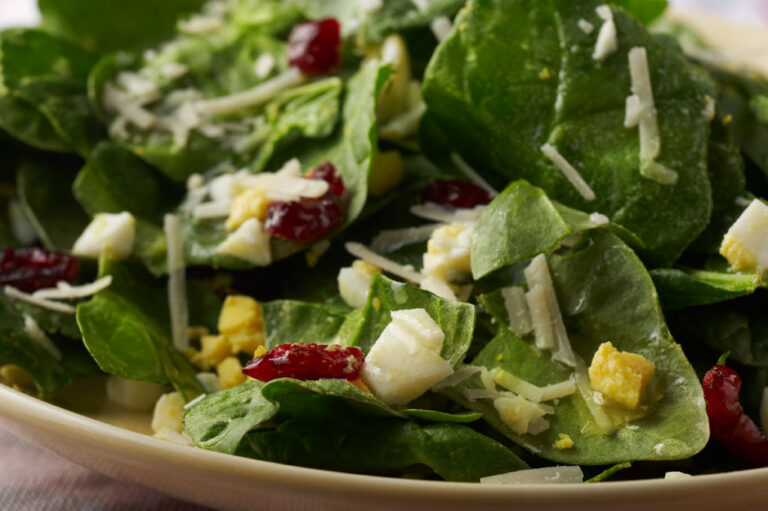 Spinach salad with eggs in a serving bowl.