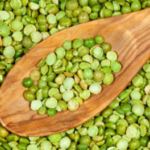 A closeup photo of wooden spoon and green split peas