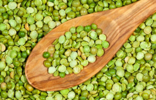 A closeup photo of wooden spoon and green split peas