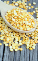A closeup photo of wooden spoon and yellow split peas