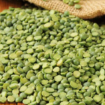 Pile of green split peas on a wooden surface.
