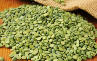 Pile of green split peas on a wooden surface.