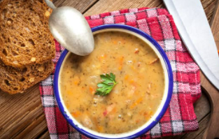 A bowl of split pea soup with roasted carrots