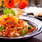 Butternut squash salsa in a purple bowl on a table with tortillas.