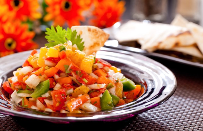 Butternut squash salsa in a purple bowl on a table with tortillas.