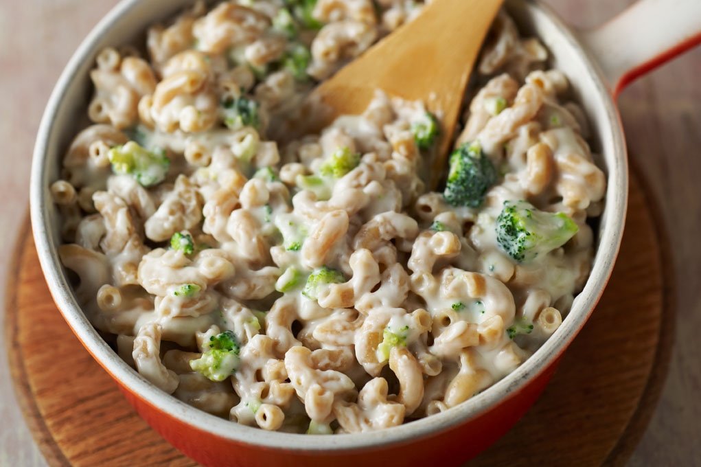 Macaroni and cheese in a bowl with a wooden spoon.