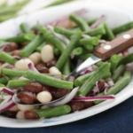 Three bean salad with green beans, kidney beans, and white beans on a white plate.