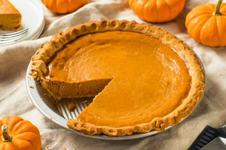 Pumpkin pie surrounded with decorative pumpkins.