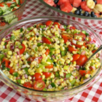 A bowl of tomato cucumber salad atop a gingham tablecloth