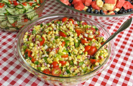 A bowl of tomato cucumber salad atop a gingham tablecloth