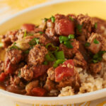 Turkey with mole sauce with rice on a white serving dish.