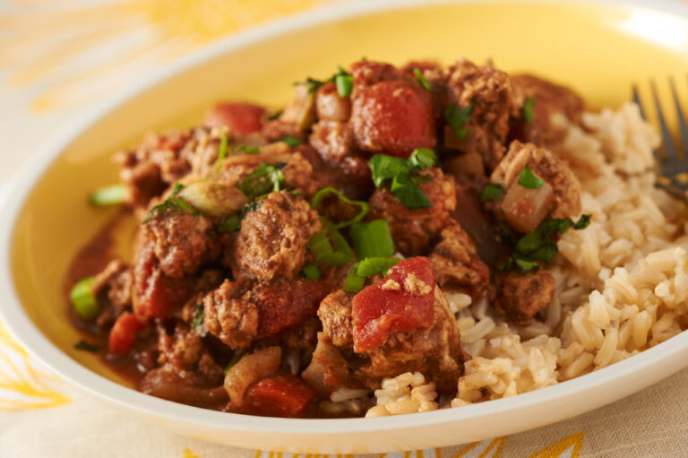 Turkey with mole sauce with rice on a white serving dish.