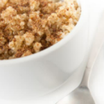 Cinnamon quinoa in a white bowl with a metal spoon.