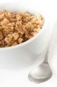 Cinnamon quinoa in a white bowl with a metal spoon.