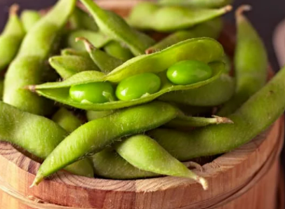 Edamame in its pod in a wooden bowl.