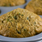 A closeup of a zucchini muffin in a muffin pan