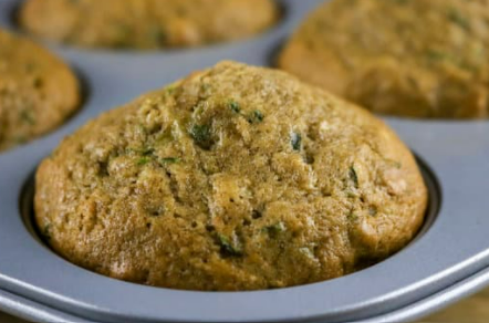 A closeup of a zucchini muffin in a muffin pan