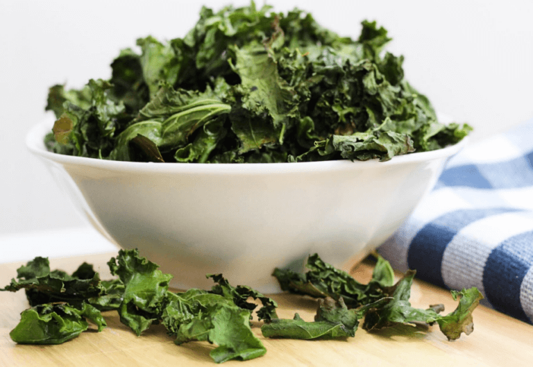 White bowl that is overflowing with kale chips.