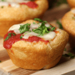 Mini PIzza Muffins with shredded cheese, tomato sauce, and fresh herbs