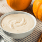 Pumpkin Yogurt Dip in a bowl with a pumpkin and cinnamon sticks