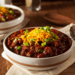 Turkey Chili in white bowl topped with cheese and green onions