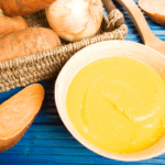 Sweet Potato Soup in a bowl with basket of sweet potatoes