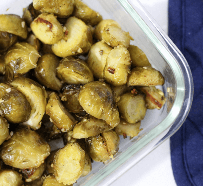 A glass dish full of roasted garlic Brussels sprouts.