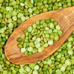Uncooked split peas with a wooden spoon.