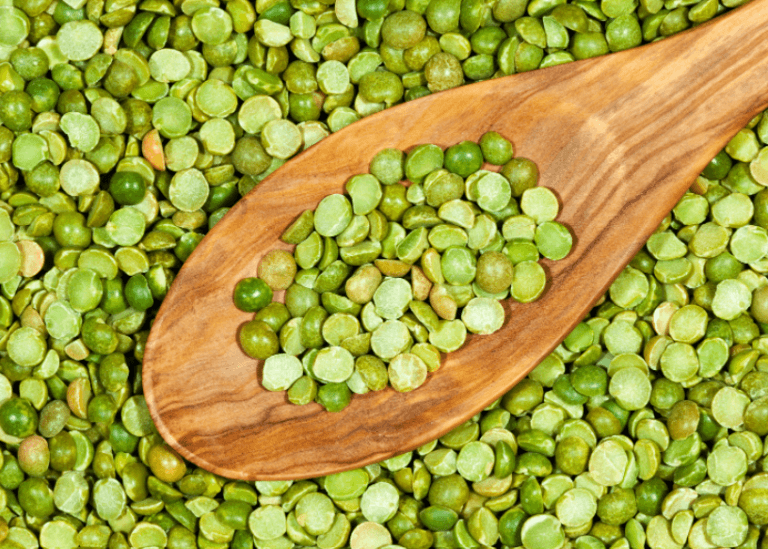 Uncooked split peas with a wooden spoon.