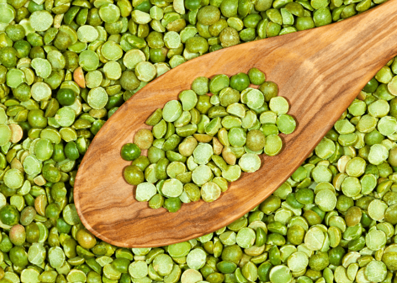 Uncooked split peas with a wooden spoon.