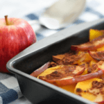 Baked apple-squash casserole in a baking dish next to a red apple.