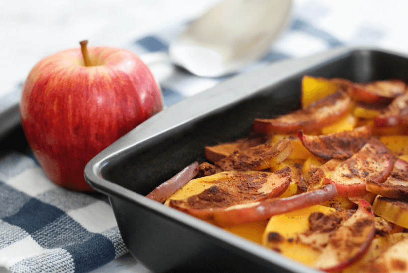 Baked apple-squash casserole in a baking dish next to a red apple.