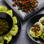 Three lettuce wraps filled with black beans and other vegetables.