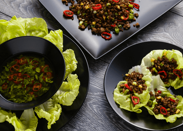 Three lettuce wraps filled with black beans and other vegetables.