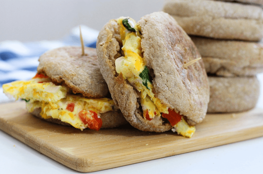 Egg bite English muffin sandwiches on a wooden cutting board.