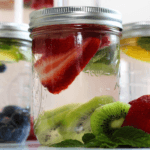 Three glass jars filled with water and different kinds of fruit.