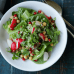 A white bowl filled with a spring salad of lettuce greens and radishes.