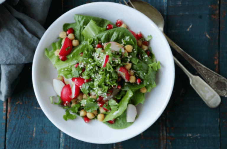 A white bowl filled with a spring salad of lettuce greens and radishes.