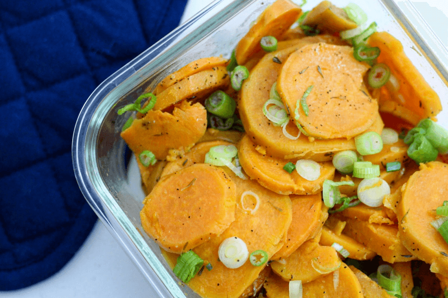 Clear dish of sweet potato salad topped with scallions and apple cider vinaigrette.
