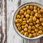 crispy roasted chickpeas in a bowl on a rustic wooden surface.