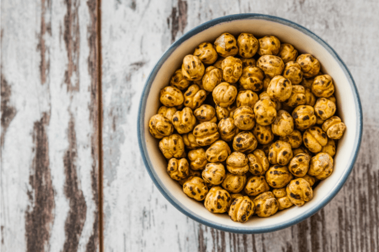 crispy roasted chickpeas in a bowl on a rustic wooden surface.