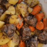 Pan-roasted lamb with potatoes and carrots in a white serving dish.