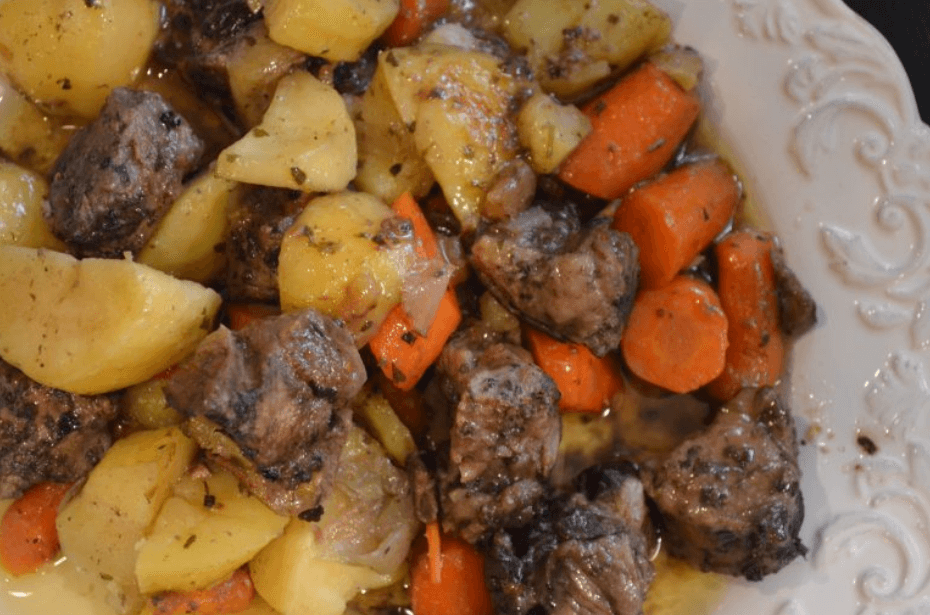 Pan-roasted lamb with potatoes and carrots in a white serving dish.