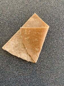 A triangle-shaped piece of dough with one corner folded on top