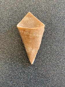 A triangle-shaped piece of dough with two corners folded on top