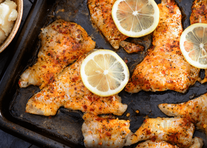 Baked catfish with Cajun seasoning and lemon slices.