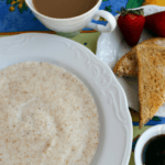 A white bowl of farina with two slices of toast, strawberries, and coffee on the side.