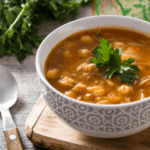 A bowl of harira with a garnished with green herbs.