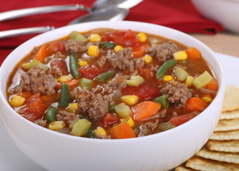 A large white bowl filled with beef and vegetable soup.