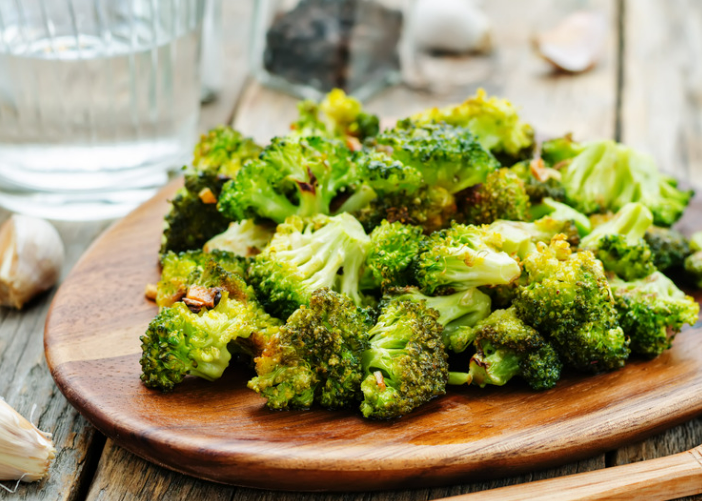Roasted broccoli on a wooden platter.